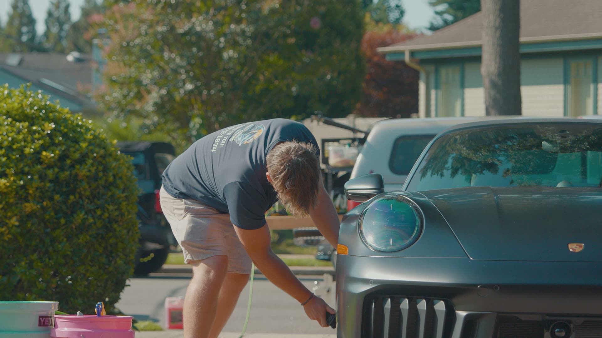 Pro Performance owner-operator working on a matte-black Porsche 911 in a residential driveway, service rig behind.